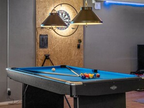Una taula de bitlles amb pilotes, un joc de daus i il·luminació penjant.