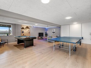 Una habitació amb taula de bitlles, taula de ping-pong i taula de billar.