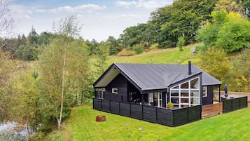 Une maison moderne avec une façade sombre, de grandes fenêtres et une terrasse.