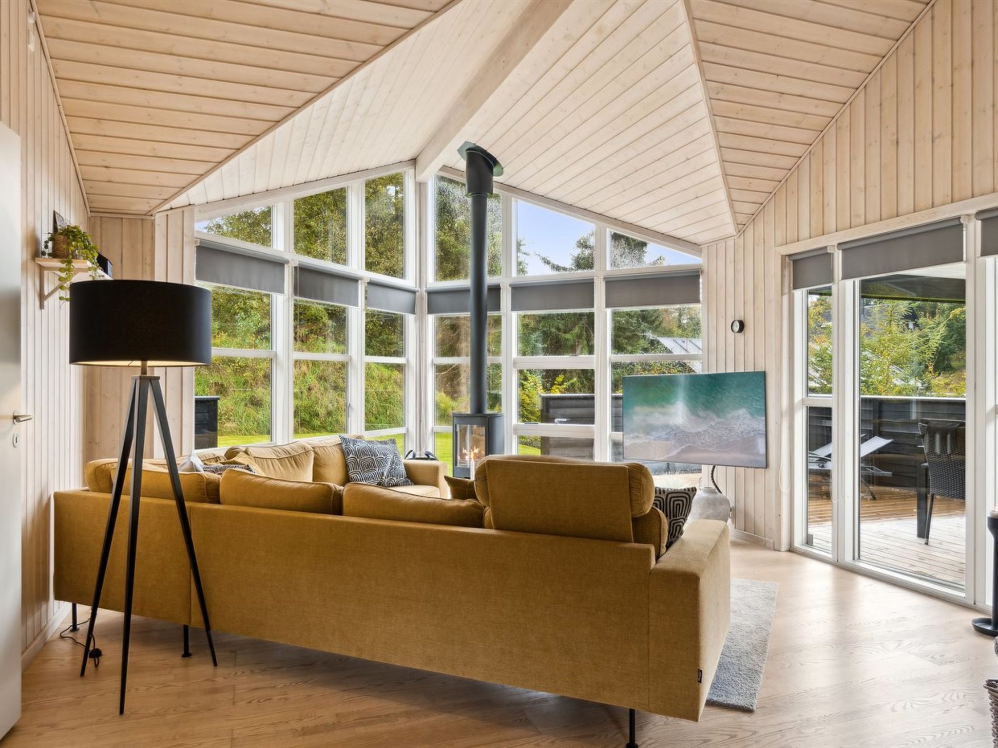 Un salon moderne avec un canapé, une lampe sur pied et une grande fenêtre donnant sur l’extérieur.