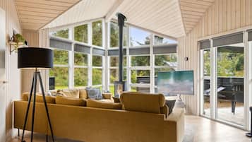 Un salon moderne avec un canapé, une lampe sur pied et une grande fenêtre donnant sur l’extérieur.