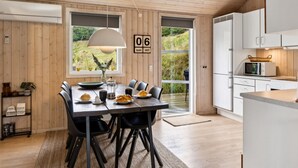 Una cucina moderna con mobili bianchi, un forno a microonde e un piccolo angolo ristoro con tavolo e sedie.