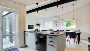 A modern kitchen with a central island, a dining area with a table and chairs, and a large window providing natural light.