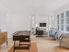 A room with a foosball table, a sofa, and a television.