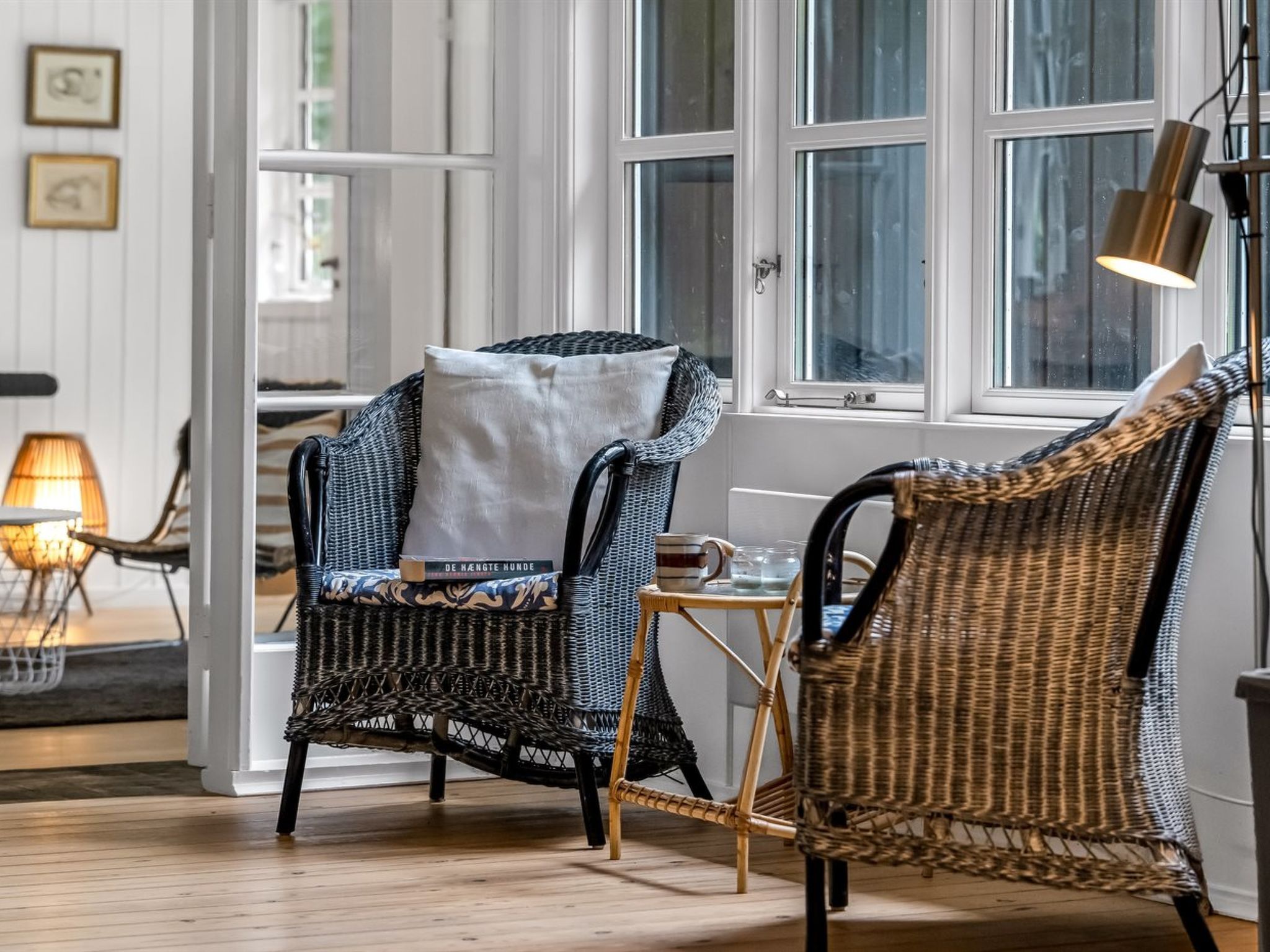 A room with wicker chairs, a small table, and a lamp.