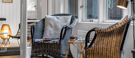 A room with wicker chairs, a small table, and a lamp.