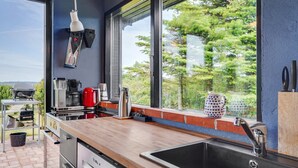 Una cocina moderna con un ventanal grande, una cafetera y un lavamanos.