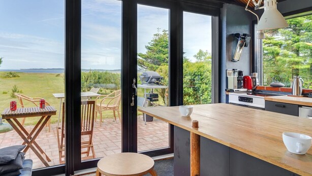 Una cocina moderna con ventanas amplias, una mesa de comedor de madera y vistas a un paisaje con césped.