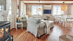 A cozy living room with a fireplace, wooden floors, and a dining area with white furniture.