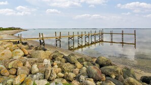 A rocky shoreline with a wooden pier extending into calm waters.