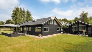 Une maison moderne à deux étages dotée d’une grande terrasse et d’un espace salon extérieur.