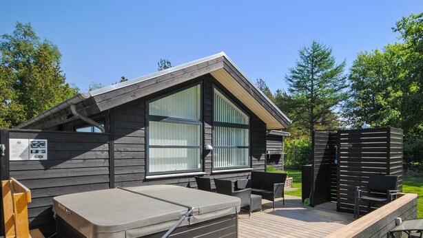 Une cabane en bois dotée d’un bain à remous, d’un espace salon extérieur et d’une terrasse.