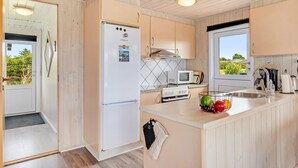 Une cuisine moderne avec des meubles blancs, un four encastré, un four à micro-ondes et un réfrigérateur.