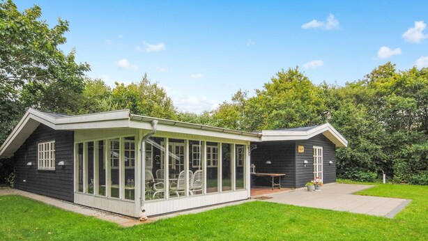Une maison moderne dotée d’un patio couvert et d’un petit jardin.