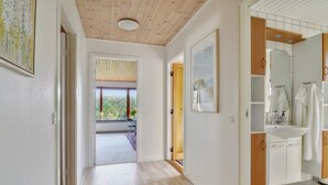 A hallway leading to a bathroom with a sink and mirror, wooden flooring, and a view of greenery outside. - "Ingward" - 750m from the sea by Interhome (Vestervig)