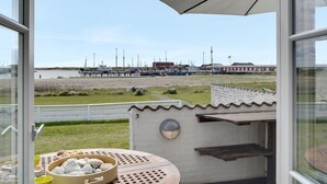 A balcony with a view of a marina, a table with a bowl of bread, and a small outdoor grill.