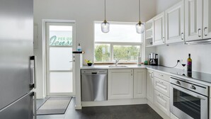 Une cuisine moderne avec des armoires blanches, des appareils en acier inoxydable et des luminaires suspendus.
