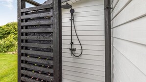Une structure de pergola en bois adossée à la façade extérieure d’une maison blanche.