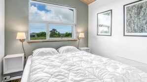 Une chambre à coucher avec un grand lit, deux tables de chevet, une fenêtre avec vue et deux lampes fixées au mur.