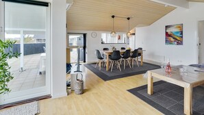 Une cuisine moderne avec des meubles en bois, un coin repas comprenant une table et des chaises en bois, et une grande fenêtre donnant sur un jardin.