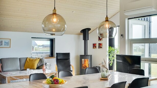 Un salon moderne avec une grande table en bois, des fauteuils en cuir noir et un luminaire en forme de dôme de verre.