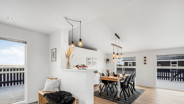 Una cocina moderna con comedor, piso de madera y vista a un balcón.