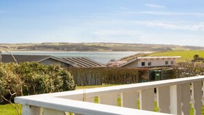 A coastal view with a wooden deck overlooking a body of water, a grassy field, and distant hills. - "Ormar" - 100m to the fjord by Interhome (Lemvig)