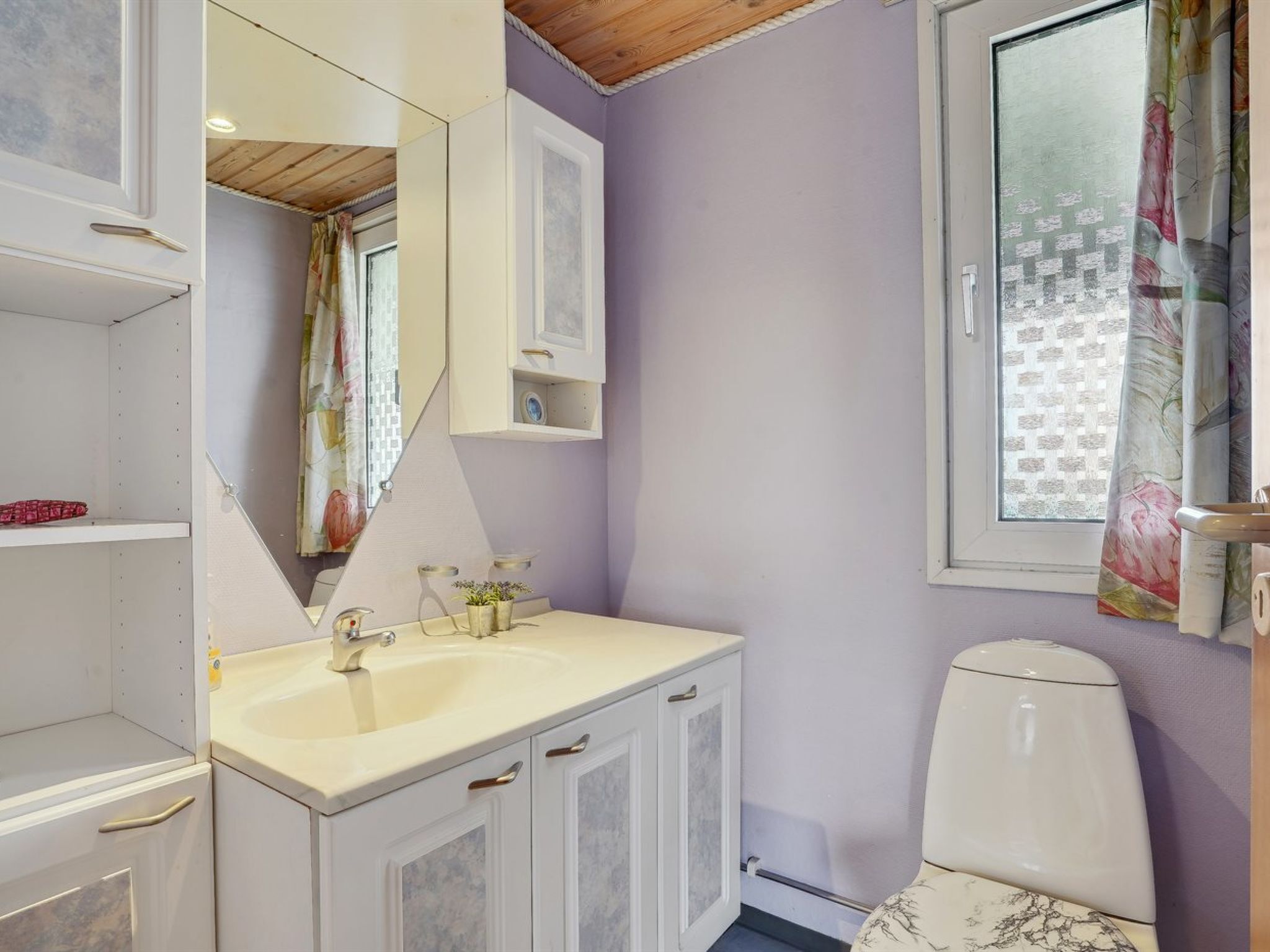 Een badkamer met een wastafel, spiegel, kastjes en toilet.