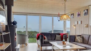 A modern living room with a fireplace, large windows, and a cozy seating area. - "Ormar" - 100m to the fjord by Interhome (Lemvig)