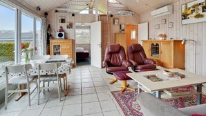 A cozy cabin interior with a dining area, two leather chairs, a sofa, and a large window offering a view of the outdoors. - "Ormar" - 100m to the fjord by Interhome (Lemvig)