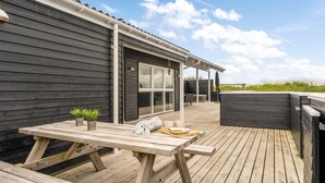 Eine Holzterrasse mit Picknicktisch, Sitzgelegenheiten im Freien und einem Whirlpool.