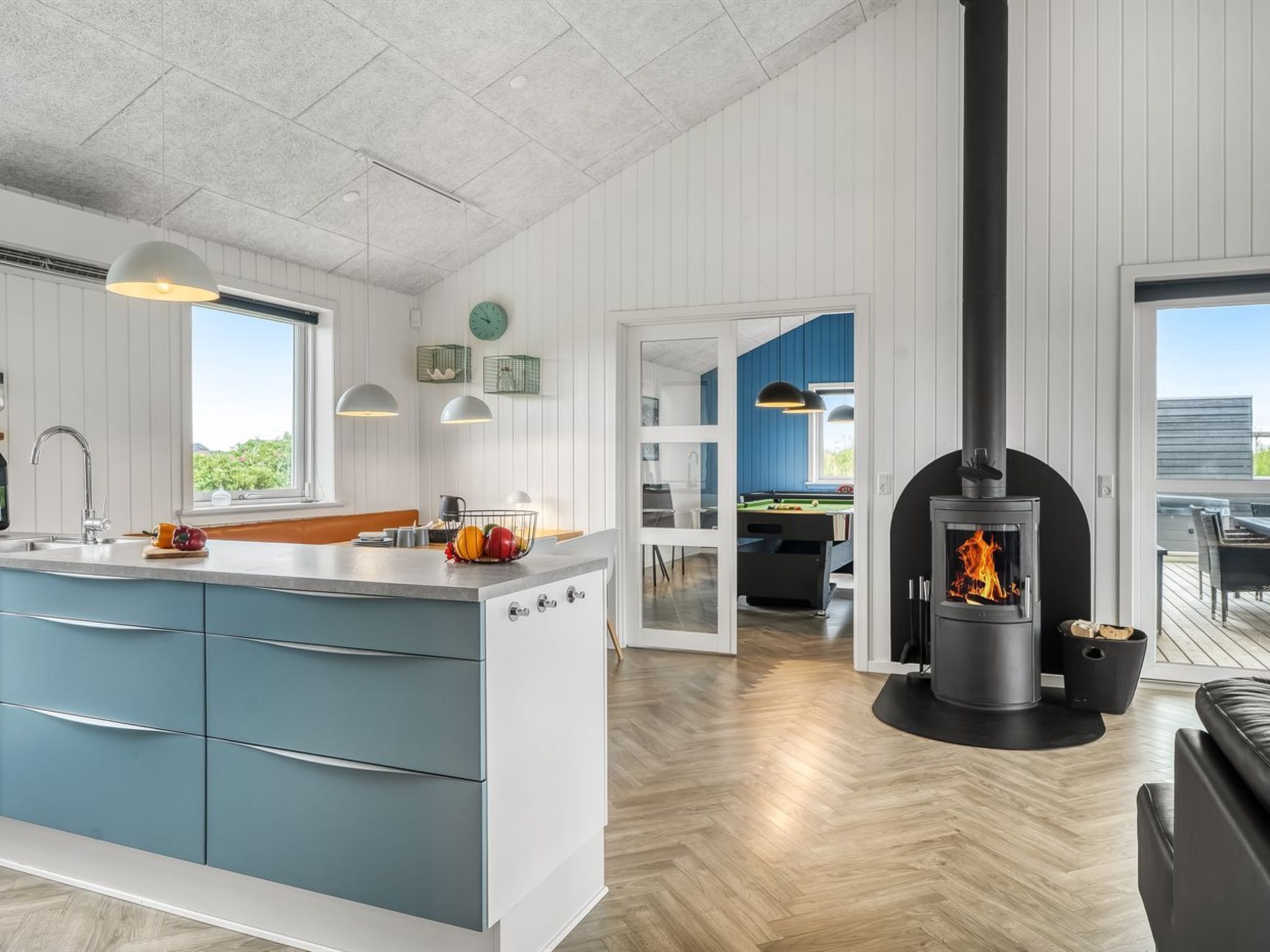 A modern kitchen with a large island, a built-in stove, and a dining area with a pool table.