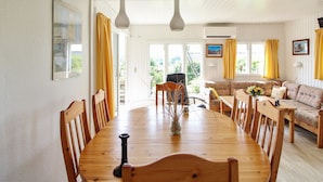 Un comedor con una mesa y sillas de madera, un sofá y un ventanal con cortinas.