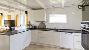 Una cocina moderna con armarios blancos, encimera negra y lavavajillas integrado.