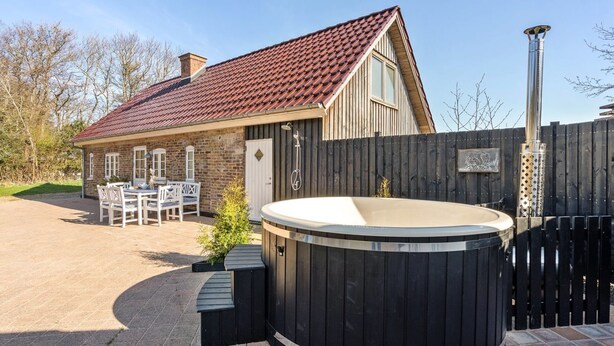 Ein Haus mit rotem Ziegeldach, einem Holzzaun und einem Whirlpool im Garten.
