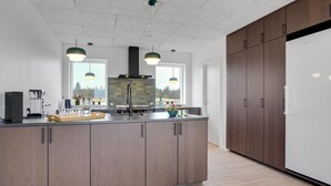 Een moderne keuken met een centraal eiland, houten kasten en hanglampen.