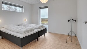 Een moderne slaapkamer met een groot bed, twee bedlampjes, een vloerlamp en uitzicht op de omgeving.