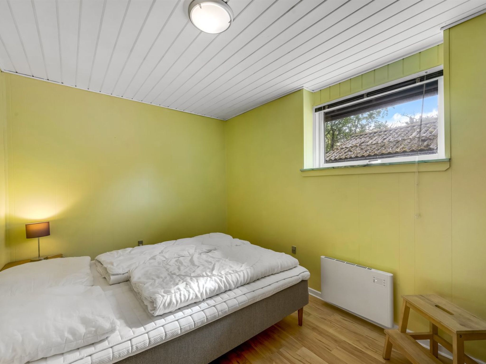 Quarto com cama, janela e radiador.