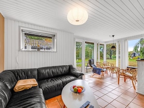 Una sala de estar moderna con un sofá de cuero negro, una mesa de centro con fruta y vistas al exterior a través de amplios ventanales.
