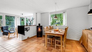 A modern kitchen with a dining area, large windows, and a fireplace.