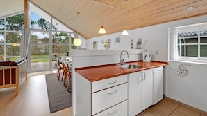 Une cuisine moderne avec des meubles en bois, un évier et une fenêtre donnant sur un jardin.