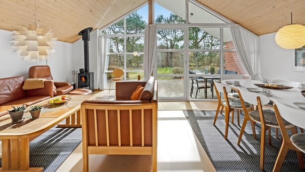 Un intérieur moderne avec une grande porte vitrée donnant sur un espace extérieur, des meubles en bois et une cheminée.