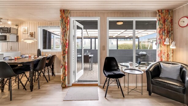Una cocina moderna con electrodomésticos integrados, un comedor con mesa y sillas, y una sala de estar con sofá y una mesa de centro.
