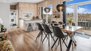 Une cuisine moderne dotée d’un îlot central, de planchers en bois et d’une grande fenêtre donnant sur un paysage magnifique.