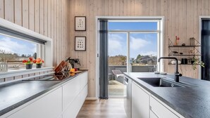 Une cuisine moderne avec des murs en bois, une grande fenêtre et une vue sur l’extérieur.