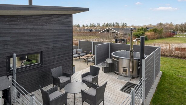 Une terrasse extérieure moderne, dotée d’un barbecue intégré, d’un espace salon et offrant une vue sur le paysage environnant.