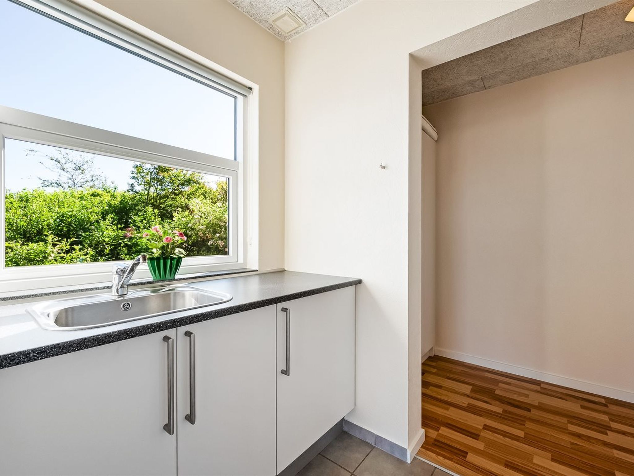 A kitchen with a window, sink, and cabinets.