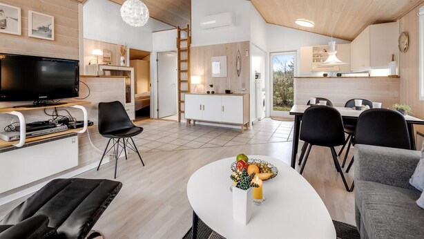 Un espacio habitable moderno y de concepto abierto con cocina, comedor y televisor en la sala.