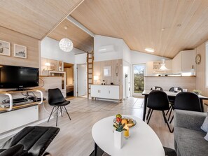 Un espacio habitable moderno y de concepto abierto con cocina, comedor y televisor en la sala.
