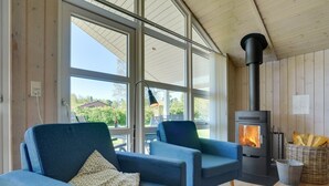 A cozy room with a large window, a fireplace, and two blue armchairs. - "Eicke" - 12km from the sea by Interhome (Oksbøl)